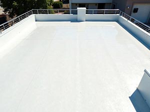 Commercial-Roofing-Contractors-Indianapolis-IN-Indiana-1 | CVC Roofing & Sheet Metal White flat rooftop or terrace with metal safety railing around the edges and nearby buildings in the background, empty and sunlit.