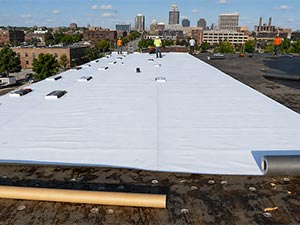 Commercial-Roofing-Contractors-Indianapolis-IN-Indiana-2 | CVC Roofing & Sheet Metal Flat white flat roof under construction with a city skyline in the distance.